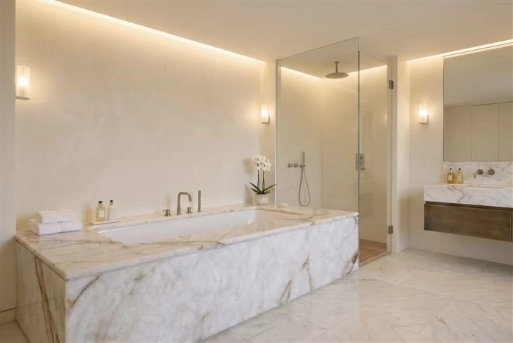 Built-in bathtub surround clad in Cristallo Quartzite with a white crystalline background and natural gold-brown veining